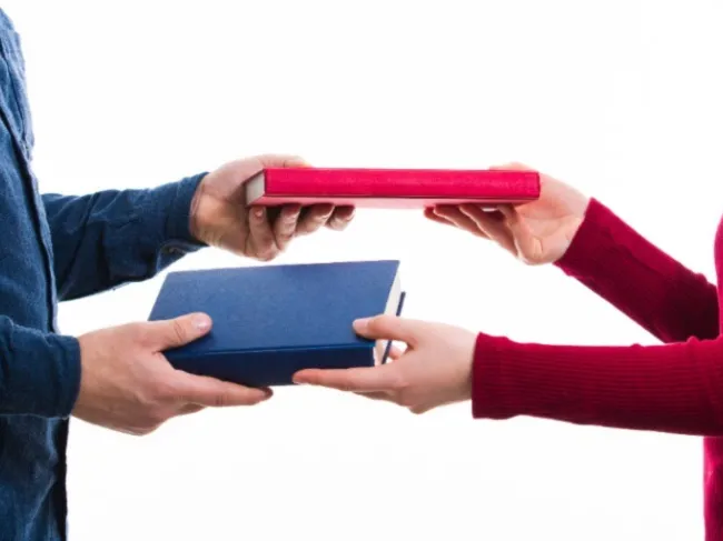 man and woman in blue and red exchanging blue and red books
